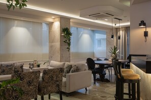 A modern living room with a sofa, chairs, a dining table, and a kitchen area with bar stools.