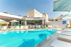 A swimming pool with lounge chairs and a bar area.