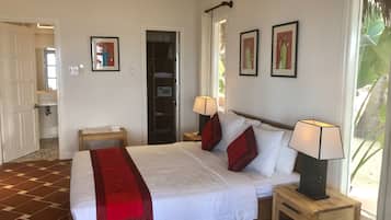Habitación de hotel con una cama grande, dos mesitas de noche con lámparas, un armario y un baño visible a través de una puerta abierta.
