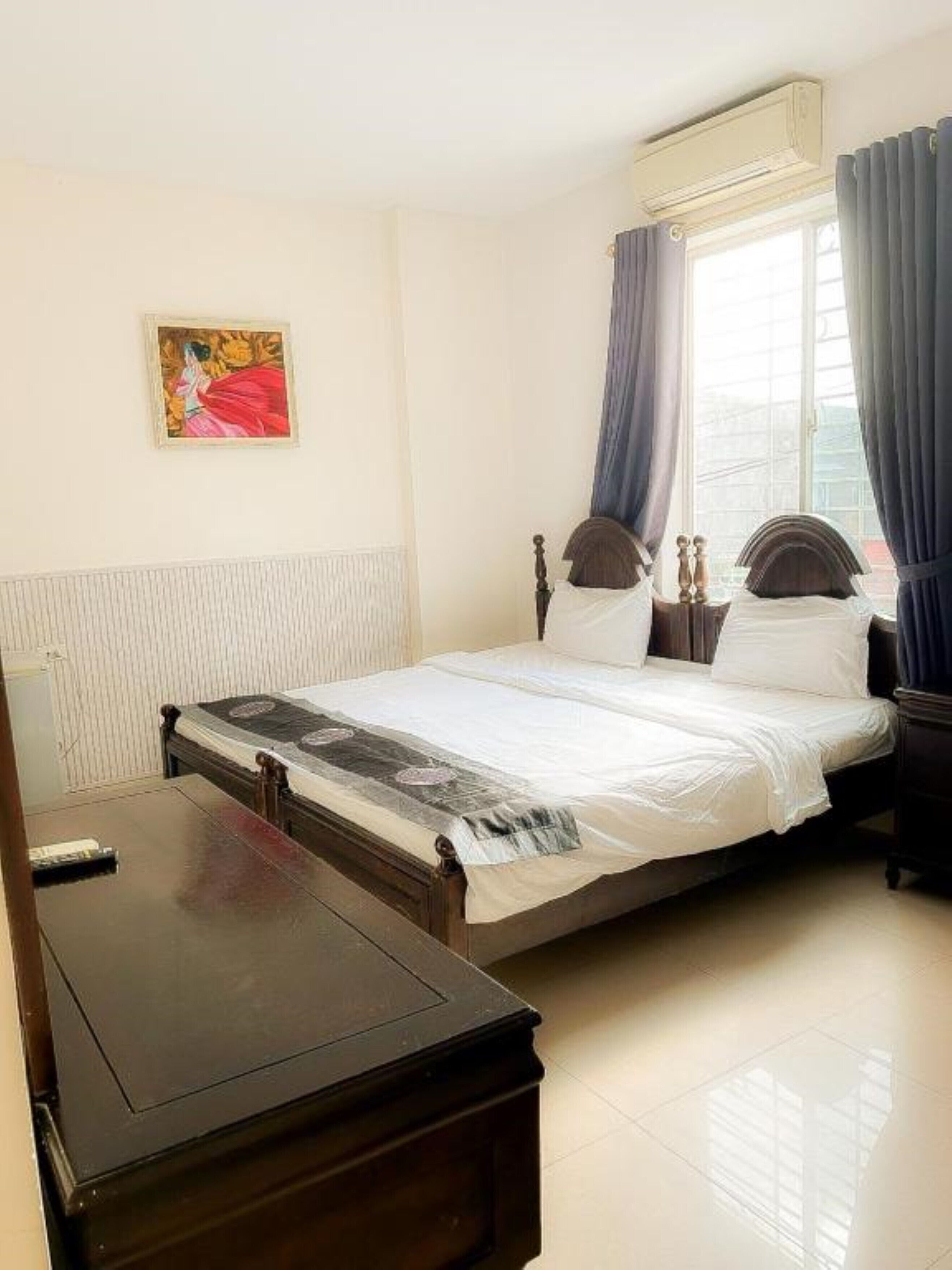 A bedroom with a bed, a bedside table, an air conditioning unit, and a window with curtains.