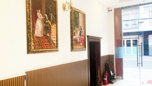 Eine Lobby mit zwei gerahmten Gemälden, einem Feuerlöscher und einem roten Teppich.