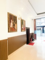 Um lobby com duas pinturas emolduradas, um extintor de incêndio e um tapete vermelho.