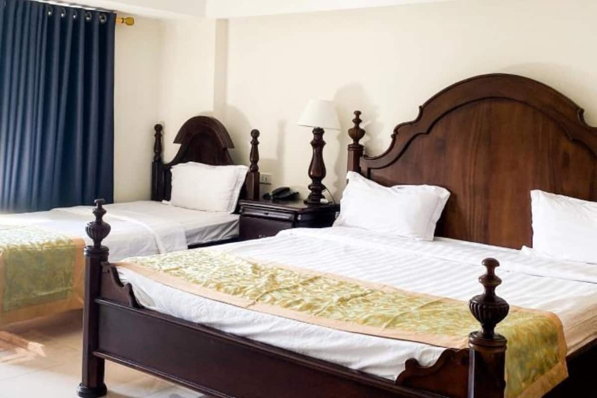 Una habitación de hotel con una cama grande, dos mesitas de noche y una mesilla.