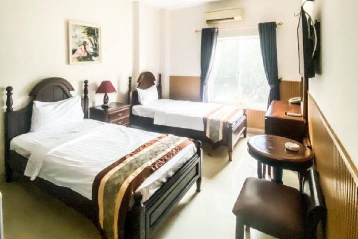 Una habitación de hotel con dos camas individuales, un escritorio, una silla y un televisor.