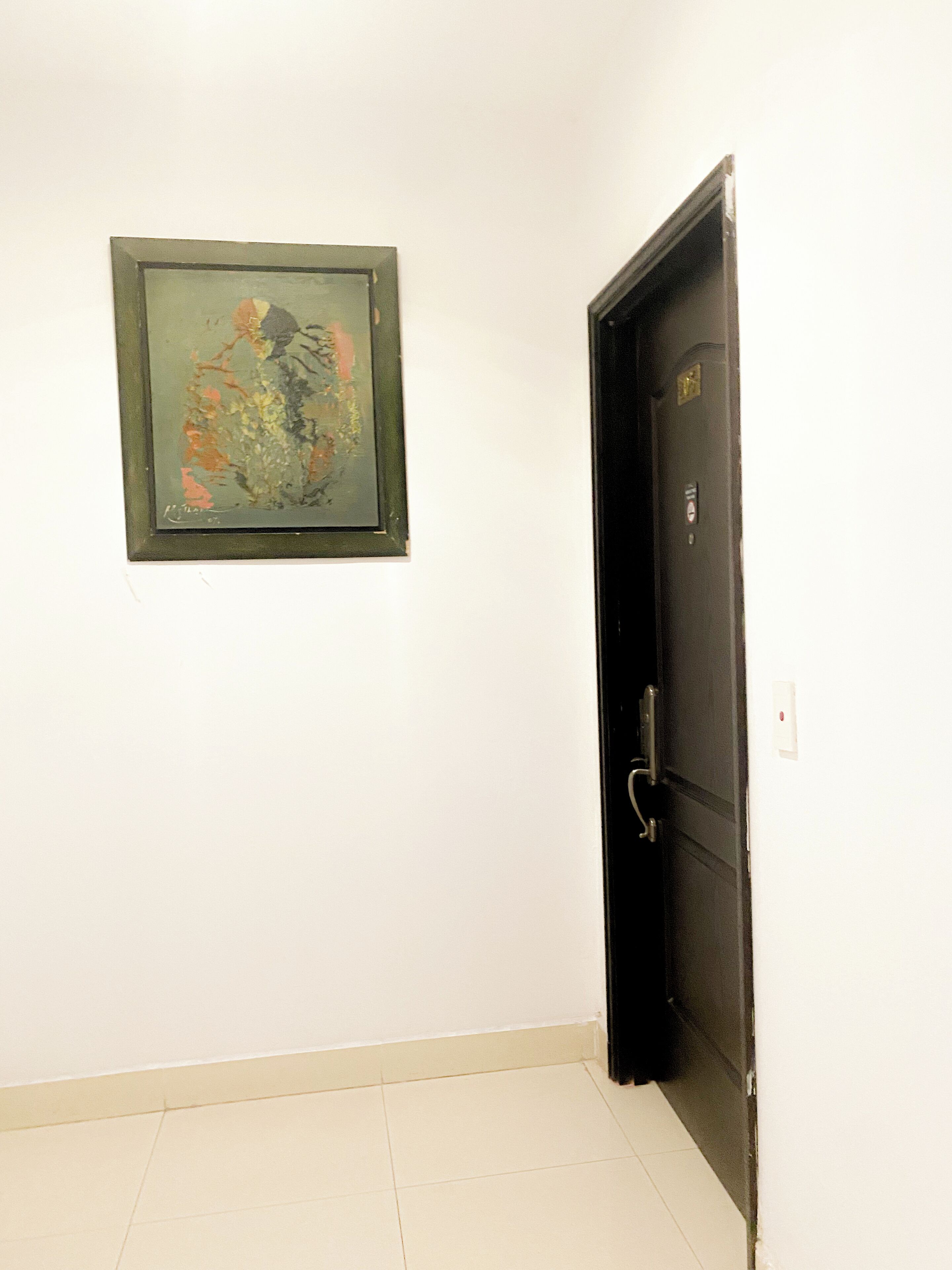 A hallway with a door and a framed abstract painting on the wall.