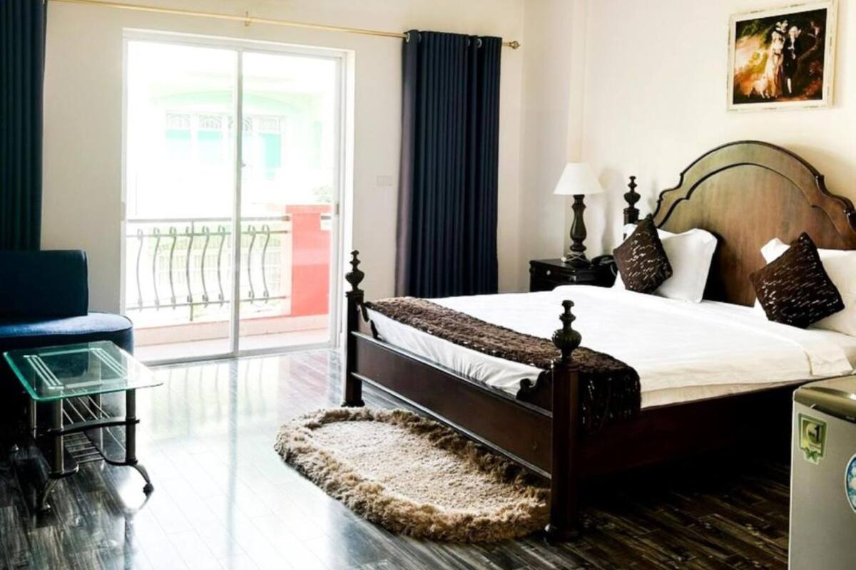 Habitación de hotel con cama, escritorio, silla, ventana con vista y puerta.