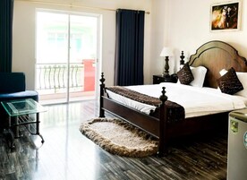 Quarto de hotel com cama, escrivaninha, cadeira, janela com vista e porta.
