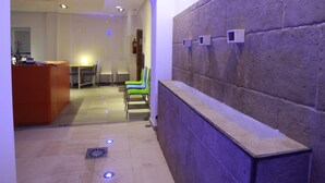 Un área de recepción moderna con una pared de piedra, mostrador de recepción y una zona de estar con sillas.
