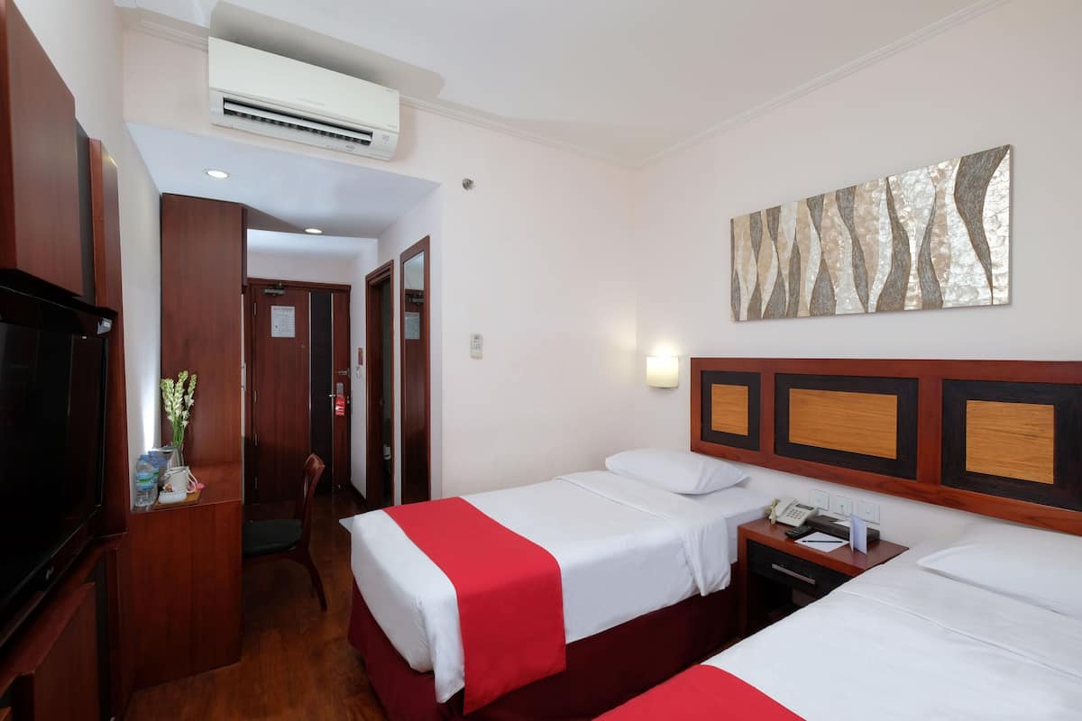 A hotel room with two beds, a TV, a desk, and a wall-mounted artwork.