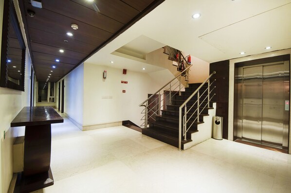 A modern interior with a staircase, an elevator, and a long corridor. - Hotel Regent Intercontinental (New Delhi)