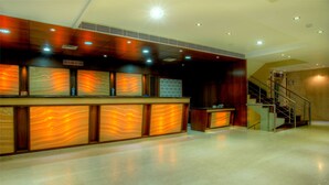 A reception desk with a marble-like design, a staircase, and a sign indicating check-in/check-out hours. - Hotel Regent Intercontinental (New Delhi)