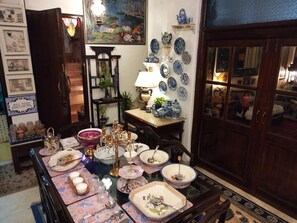 A dining area with a table set for a meal, surrounded by various decorative items and a wall of blue and white plates. - On The House - Bed and Breakfast (New Delhi)