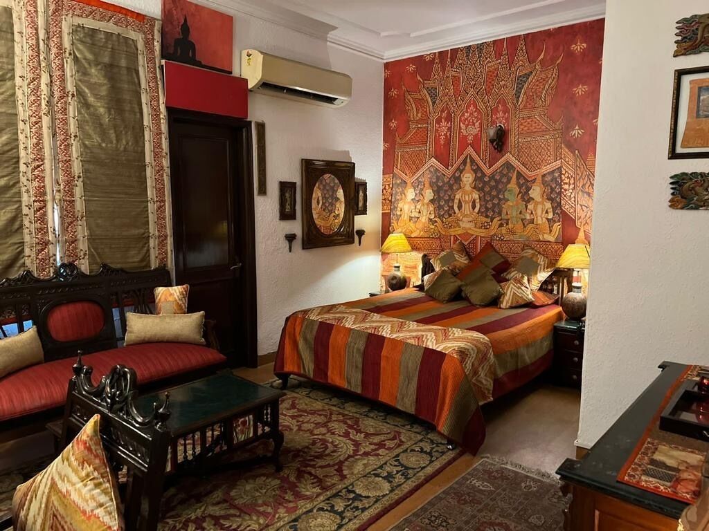 Une chambre traditionnelle avec un lit, un canapé et une tapisserie décorative au mur.