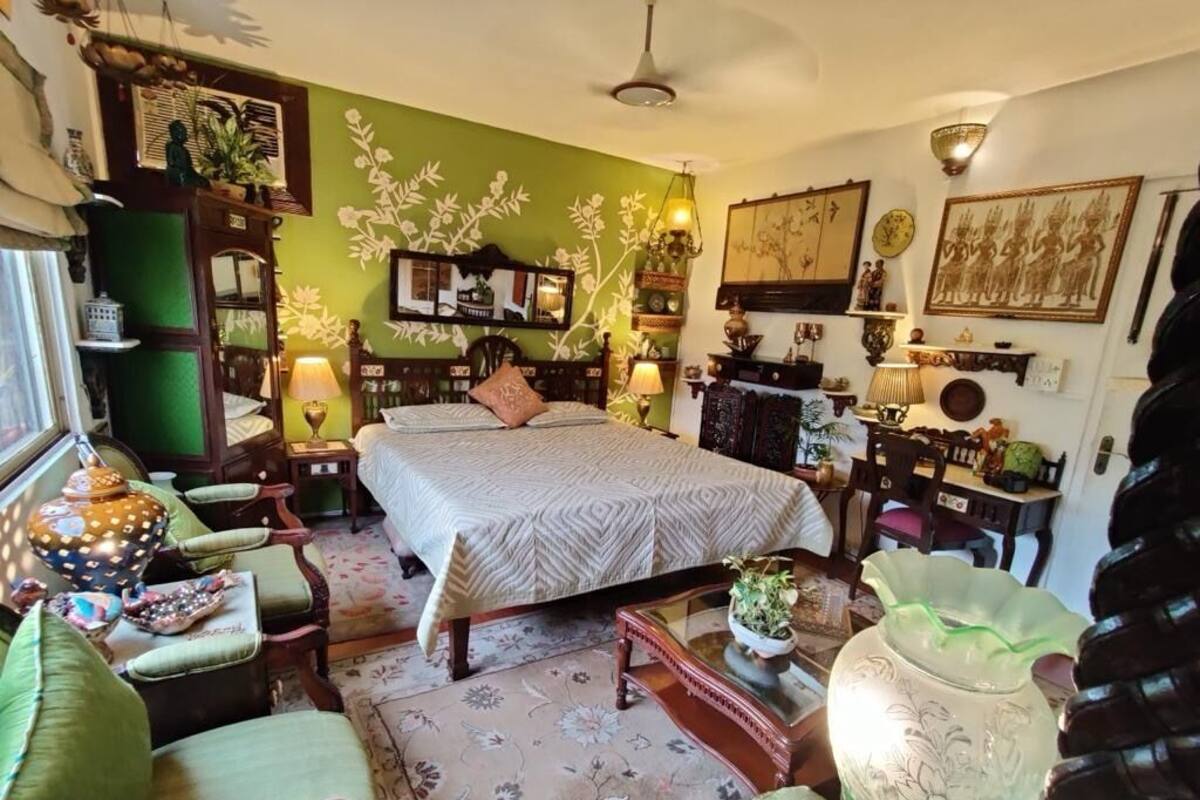 A room with a bed, a chair, a table, and a lamp.