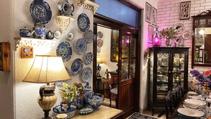 A room with a wall adorned with blue and white patterned plates, a wooden cabinet with glass doors, and a table with blue and white ceramic items. - On The House - Bed and Breakfast (New Delhi)