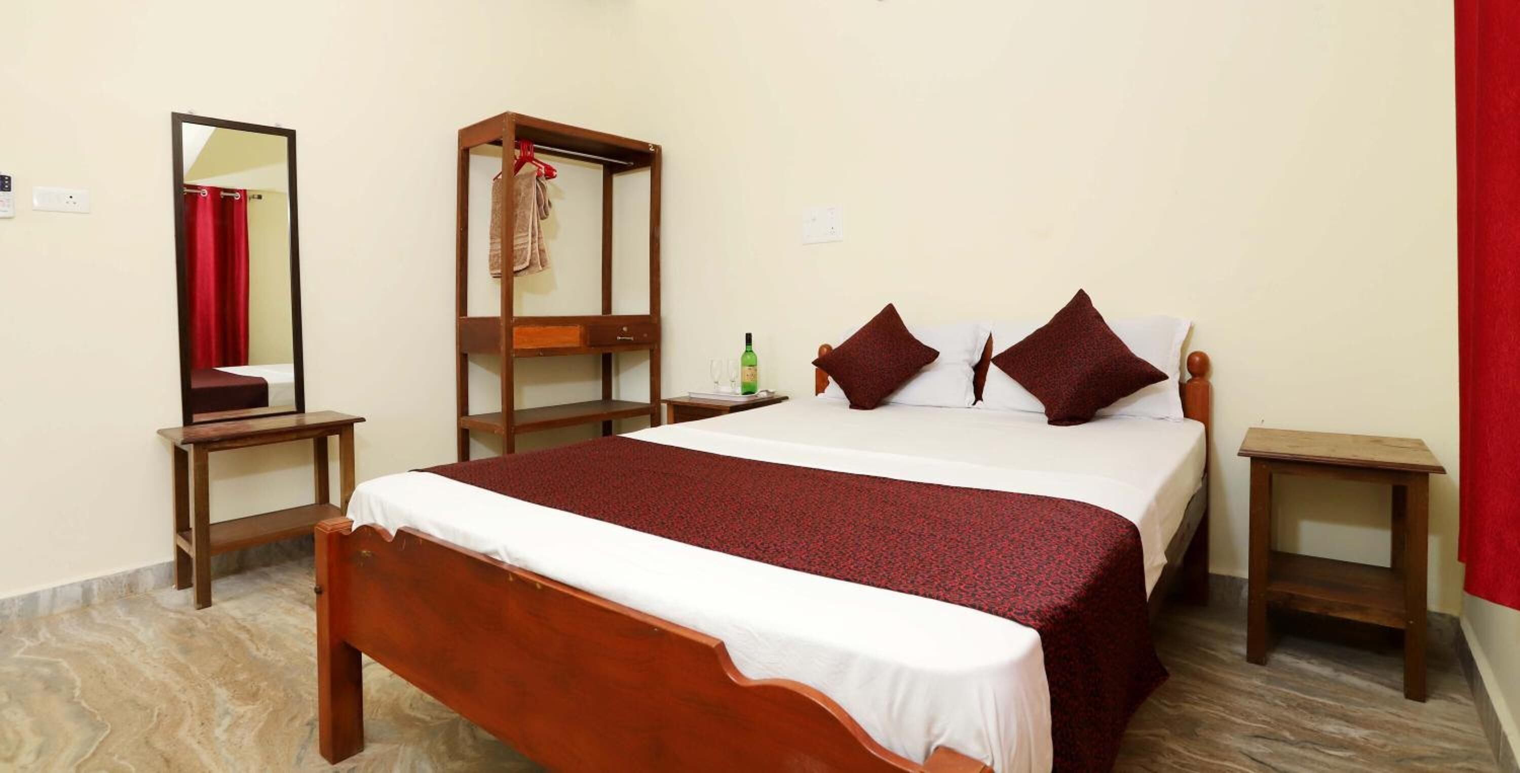 Habitación de hotel con una cama de madera, un espejo, un armario y una mesita.