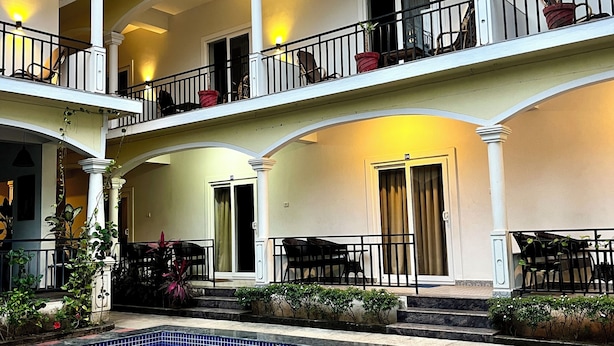 A multi-level hotel with a central pool area, balconies with railings, and outdoor seating. - Morjim Sunset Hotel (Morjim)