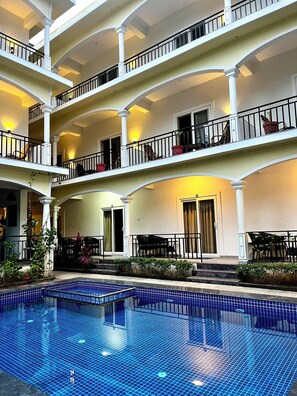 A multi-level hotel with a central pool area, balconies with railings, and outdoor seating. - Morjim Sunset Hotel - 300 Meter to Morjim Beach with Pool & Kitchen Apartments (Morjim)