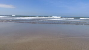 A beach with waves approaching the shore under a clear sky. - Morjim Sunset Hotel (Morjim)