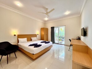 A hotel room with a bed, a desk, a chair, a ceiling fan, and a TV. - Morjim Sunset Hotel - 300 Meter to Morjim Beach with Pool & Kitchen Apartments (Morjim)