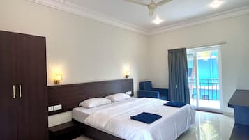 Ein Hotelzimmer mit Bett, Schreibtisch, Stuhl, Deckenventilator und Blick ins Freie.