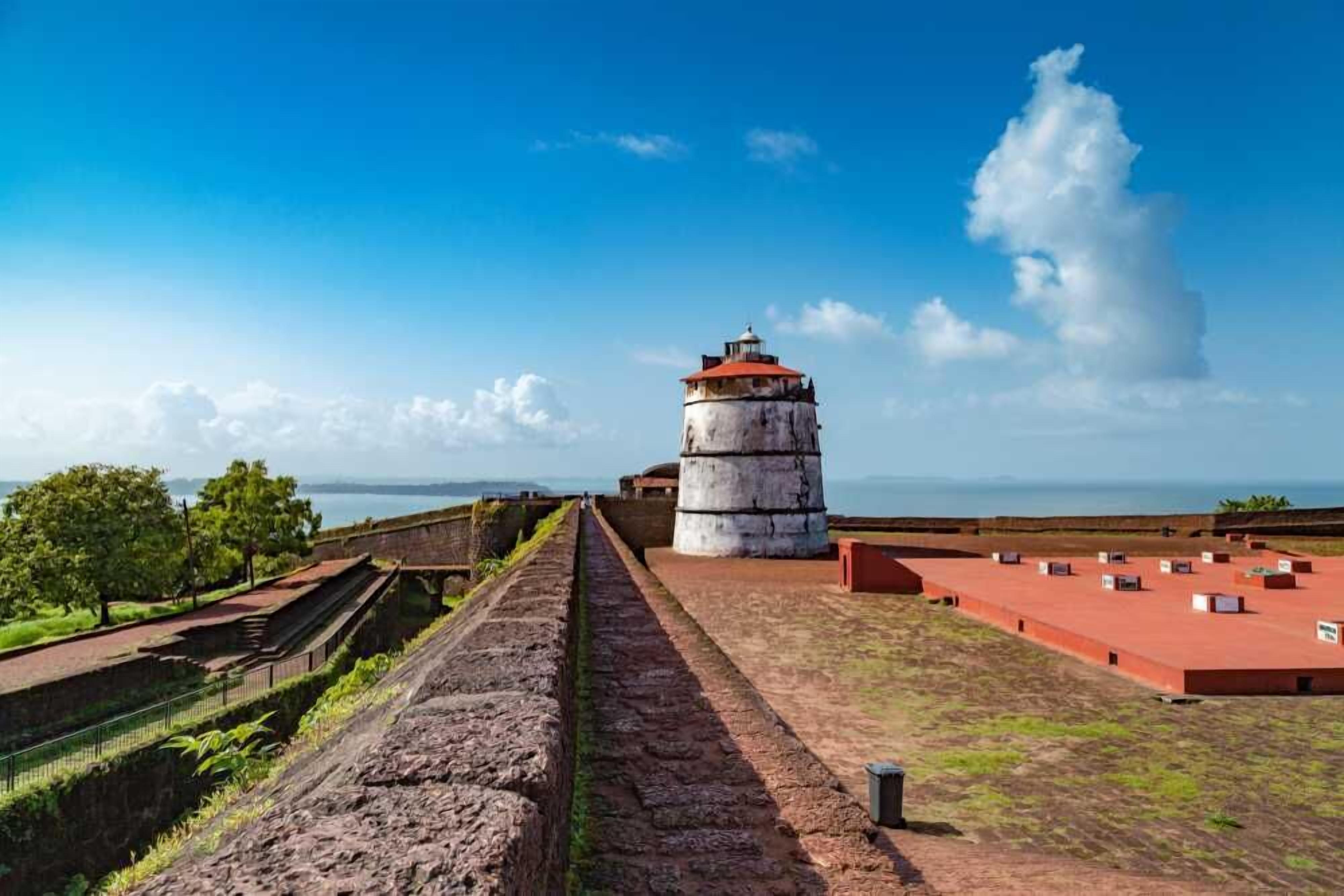 A historical fort with a central tower, a paved walkway, and a view of the sea.