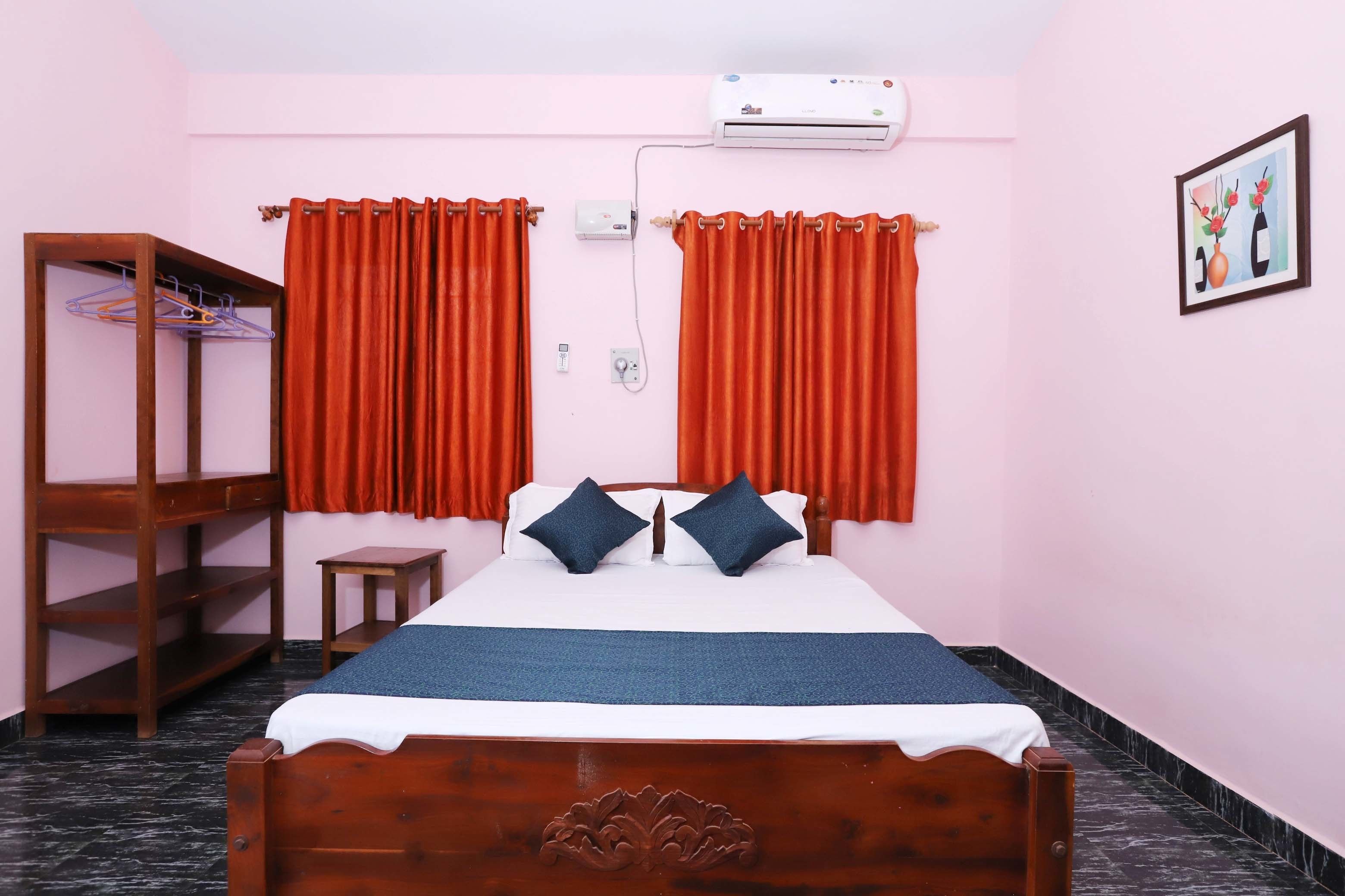 Une chambre à coucher avec un lit en bois, des rideaux rouges, une petite table de chevet, une armoire et un climatiseur fixé au mur.