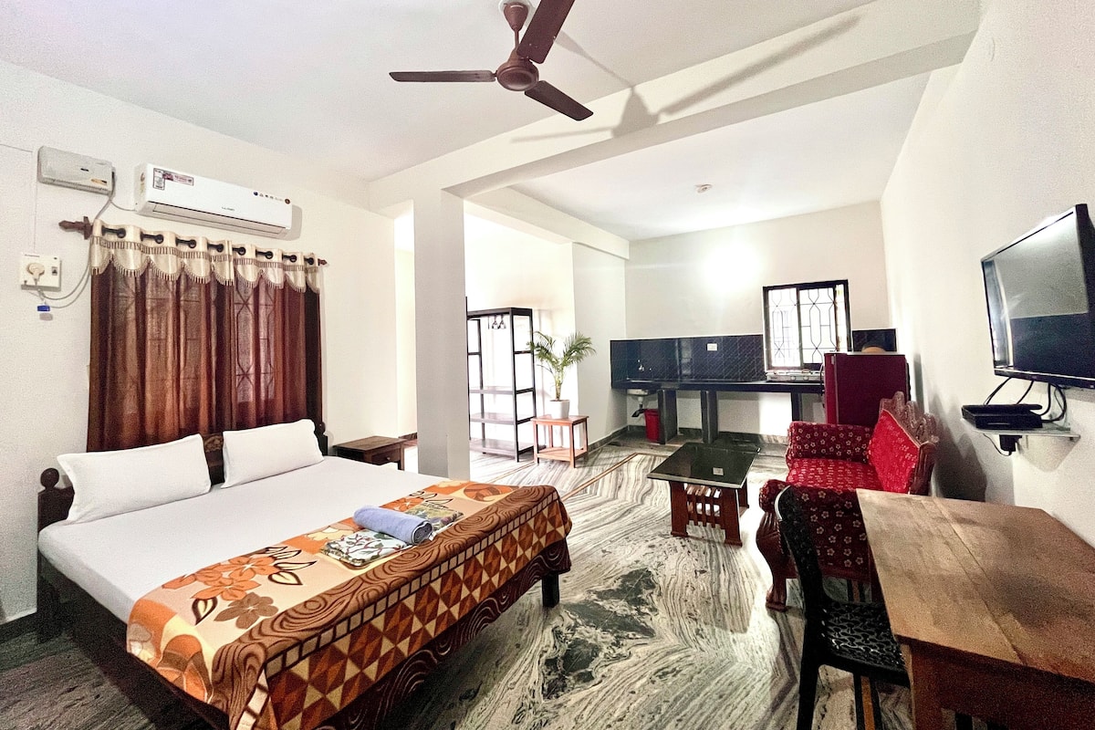 A hotel room with a bed, a desk, a chair, a television, and a ceiling fan.