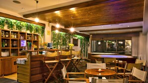 Ein Restaurant mit Holztischen, einer Bar und einer grünen Wand mit Pflanzen.