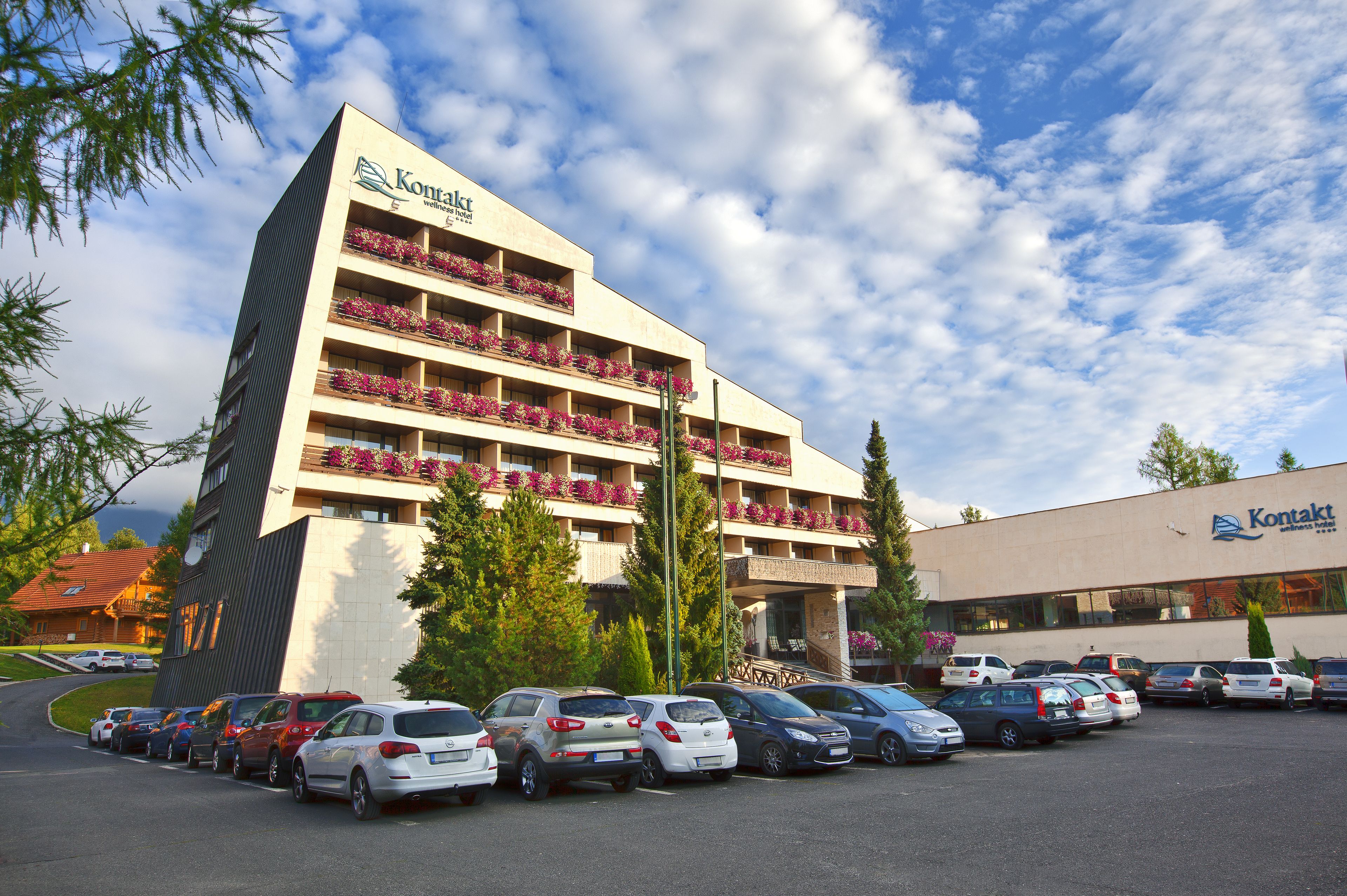 A hotel with multiple balconies, a parking lot, and a clear sky.