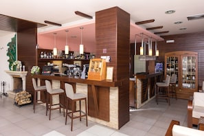 Un espace bar doté de comptoirs en bois, de tabourets de bar et de luminaires suspendus.