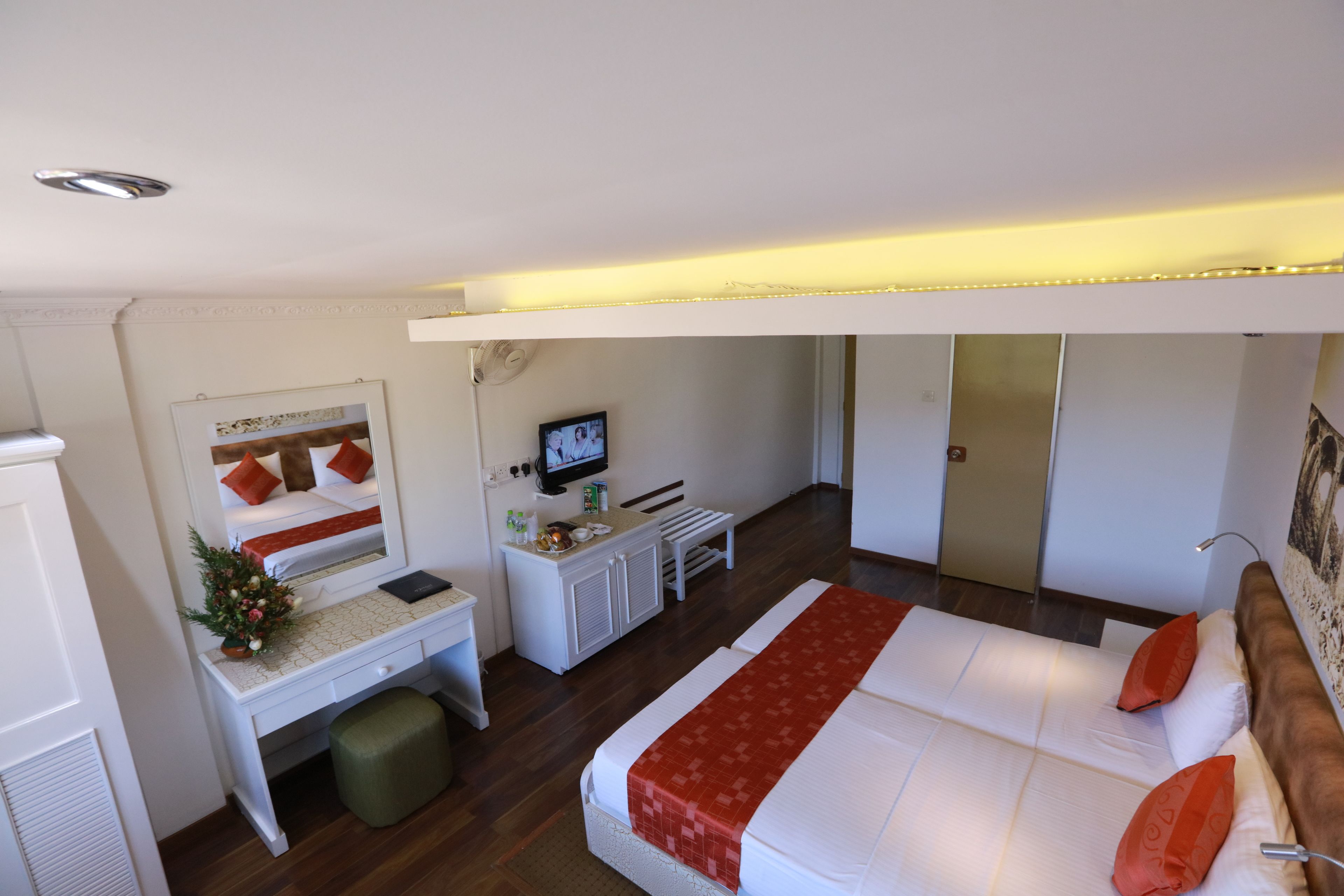 Habitación de hotel con cama, escritorio, televisor y espejo.