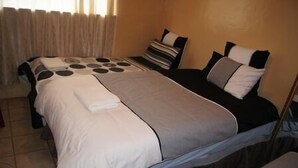 Ein Hotelzimmer mit Bett, Nachttisch und einem fenster mit Vorhängen.