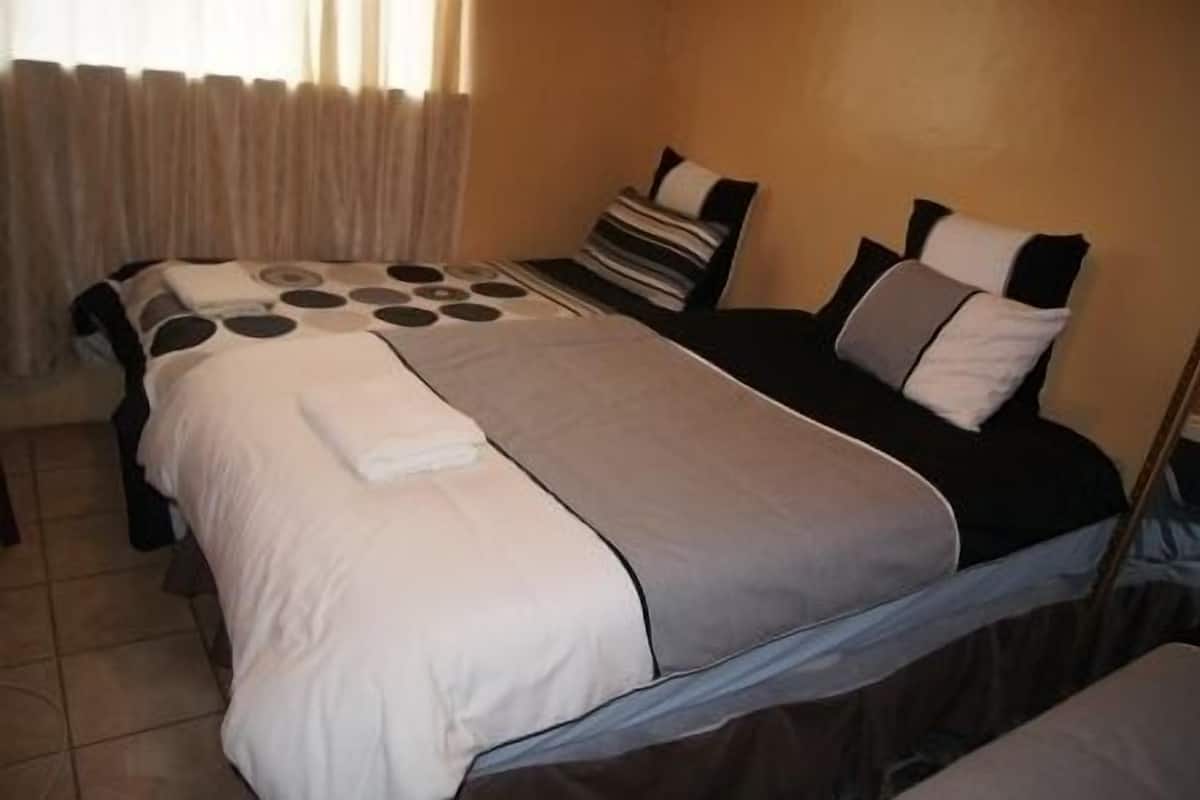 Une chambre d’hôtel avec un lit, une table de chevet et une fenêtre avec des rideaux.