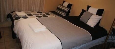 A hotel room with a bed, a bedside table, and a window with curtains.
