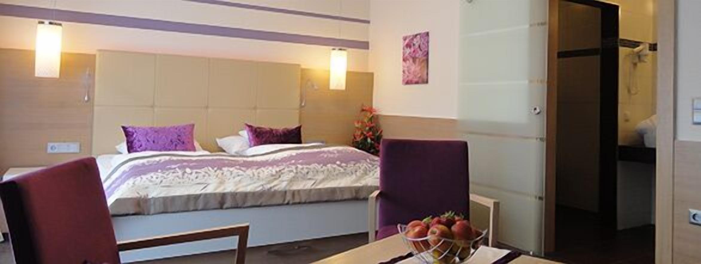 Ein Hotelzimmer mit Bett, Sessel, Tisch mit Obst und Duschbereich.