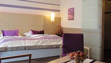 Ein Hotelzimmer mit Bett, Sessel, Tisch mit Obst und Duschbereich.