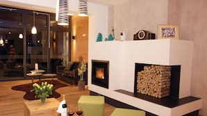 Un salon moderne avec une cheminée, des meubles en bois et une porte vitrée donnant sur un espace repas.