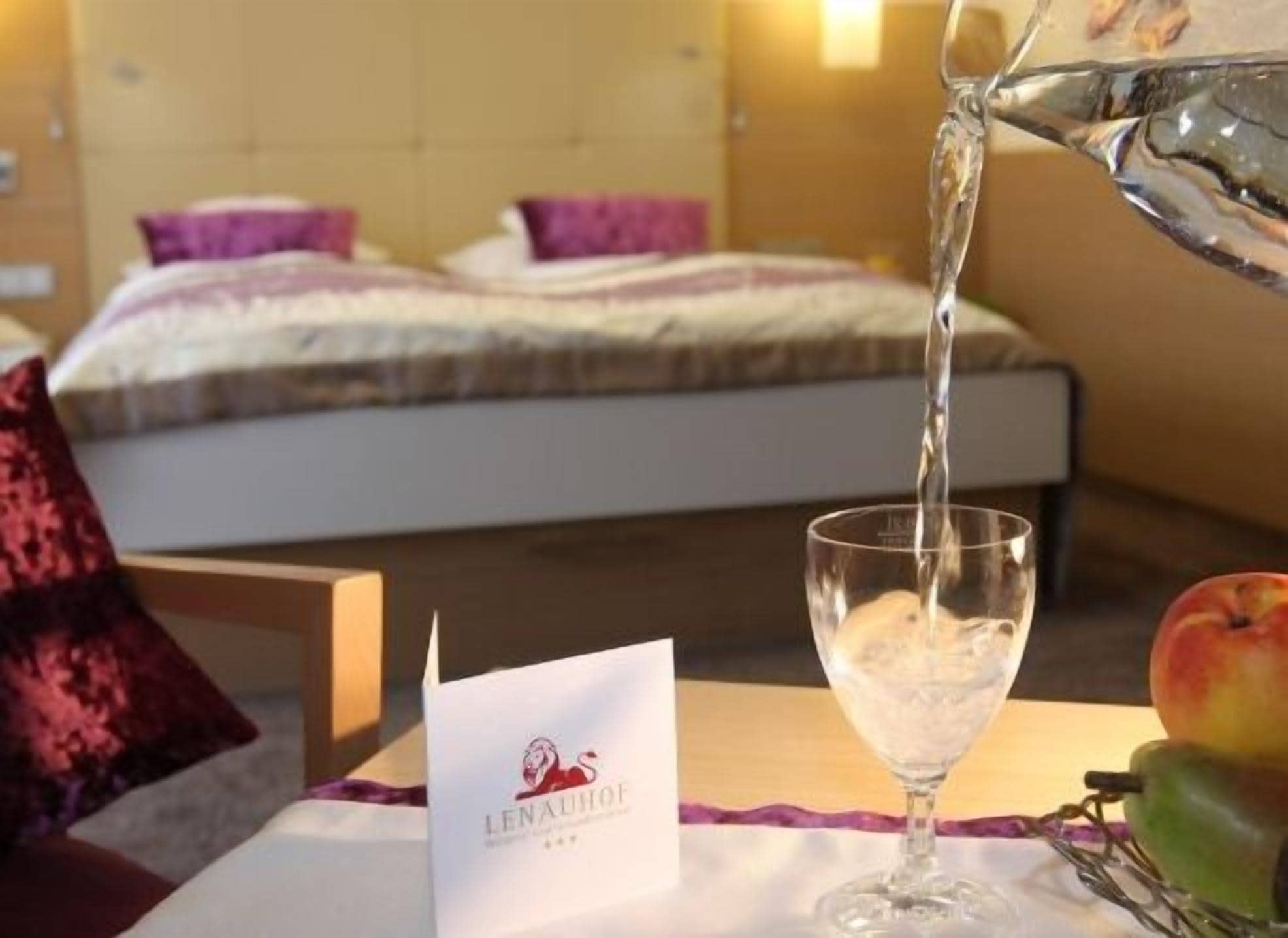 Une chambre d’hôtel avec un lit, un verre d’eau et un fruit sur la table.