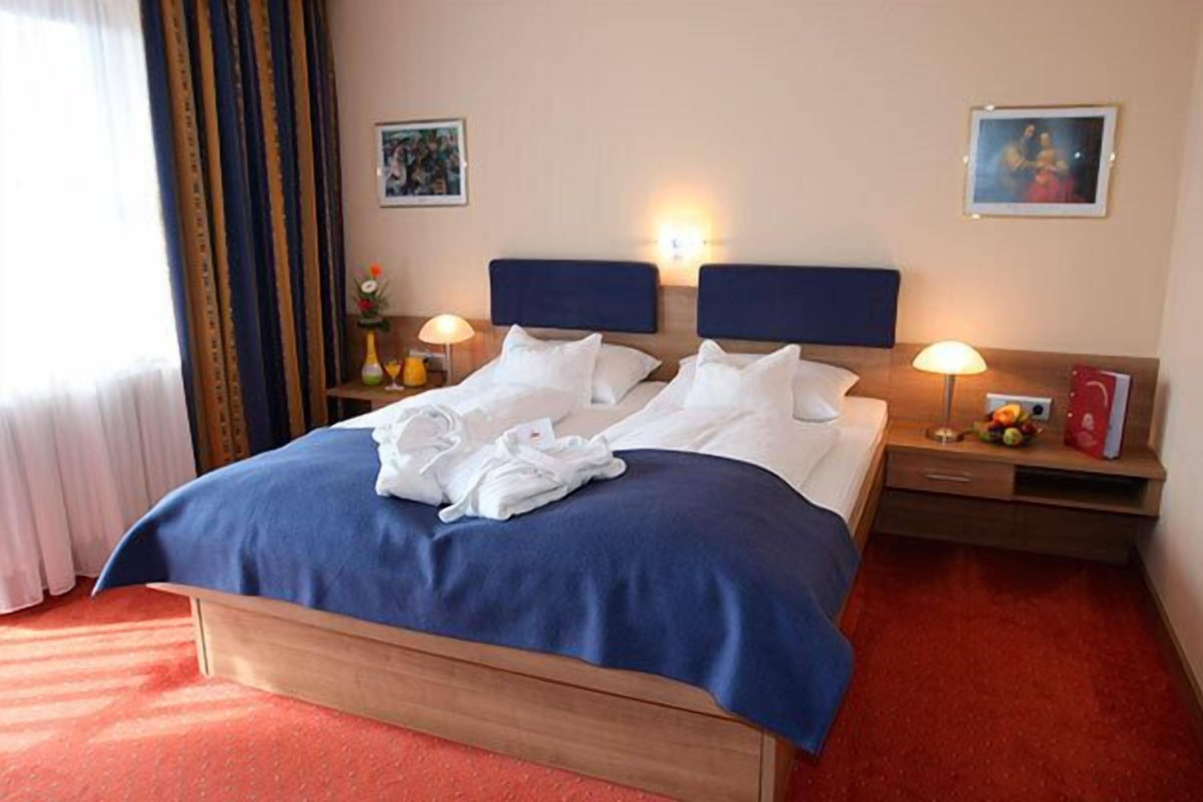 A hotel room with a large bed, two bedside tables, and a nightstand.