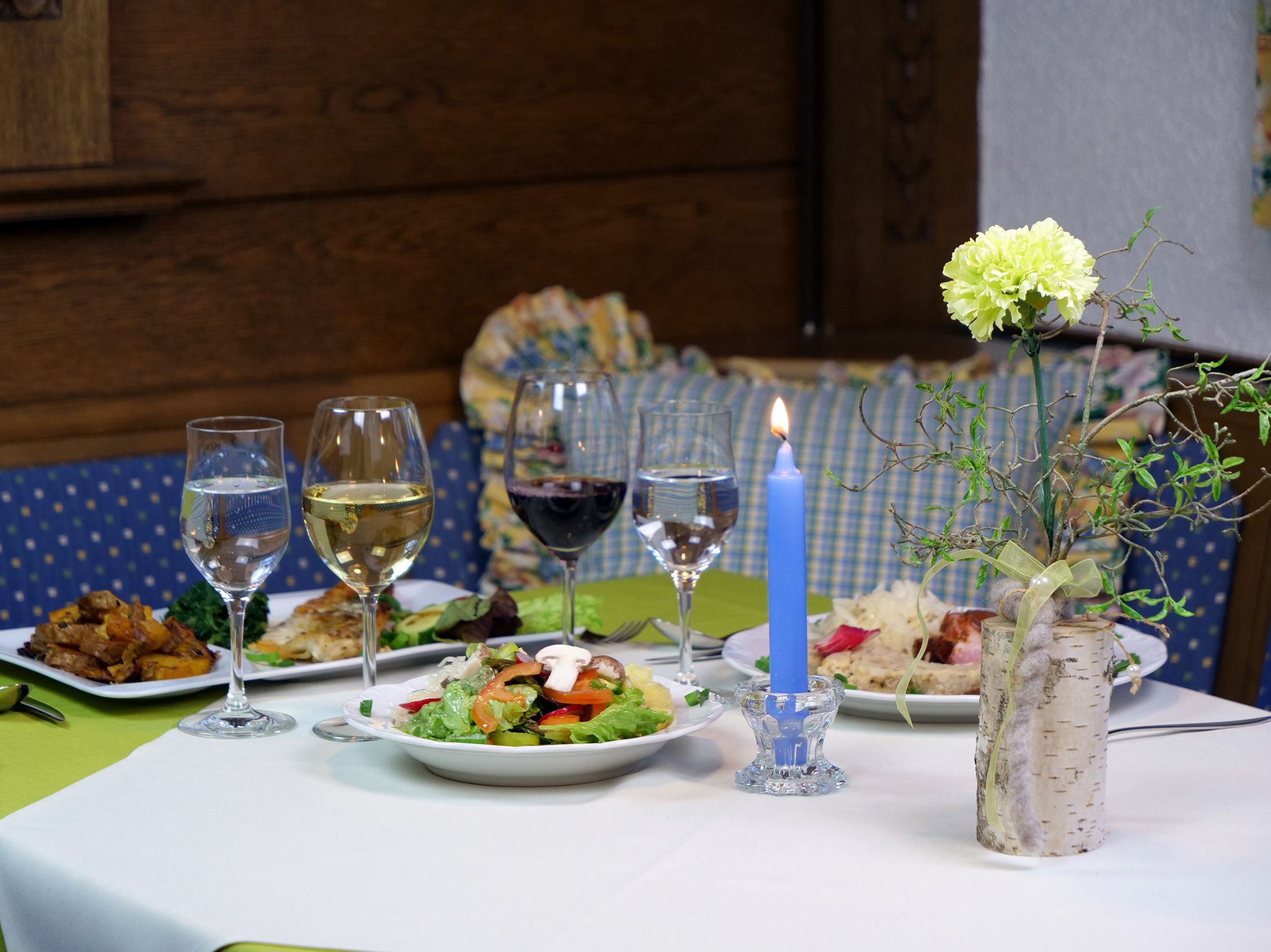 A dining table with plates of food, glasses of wine, and a candle.