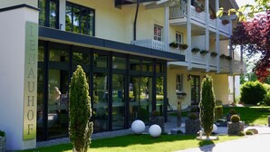 Un hôtel doté d’une façade moderne, de grandes fenêtres et d’un jardin bien entretenu, agrémenté de jardinières sphériques et de haies soigneusement taillées.