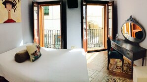 Un dormitorio con cama, cómoda, espejo y balcón con vistas al exterior.