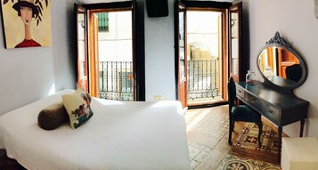 Un dormitorio con cama, cómoda, espejo y balcón con vistas al exterior.