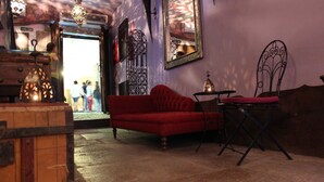 Una habitación acogedora con un sofá rojo, una mesita con una lámpara y detalles decorativos de metal en las paredes.