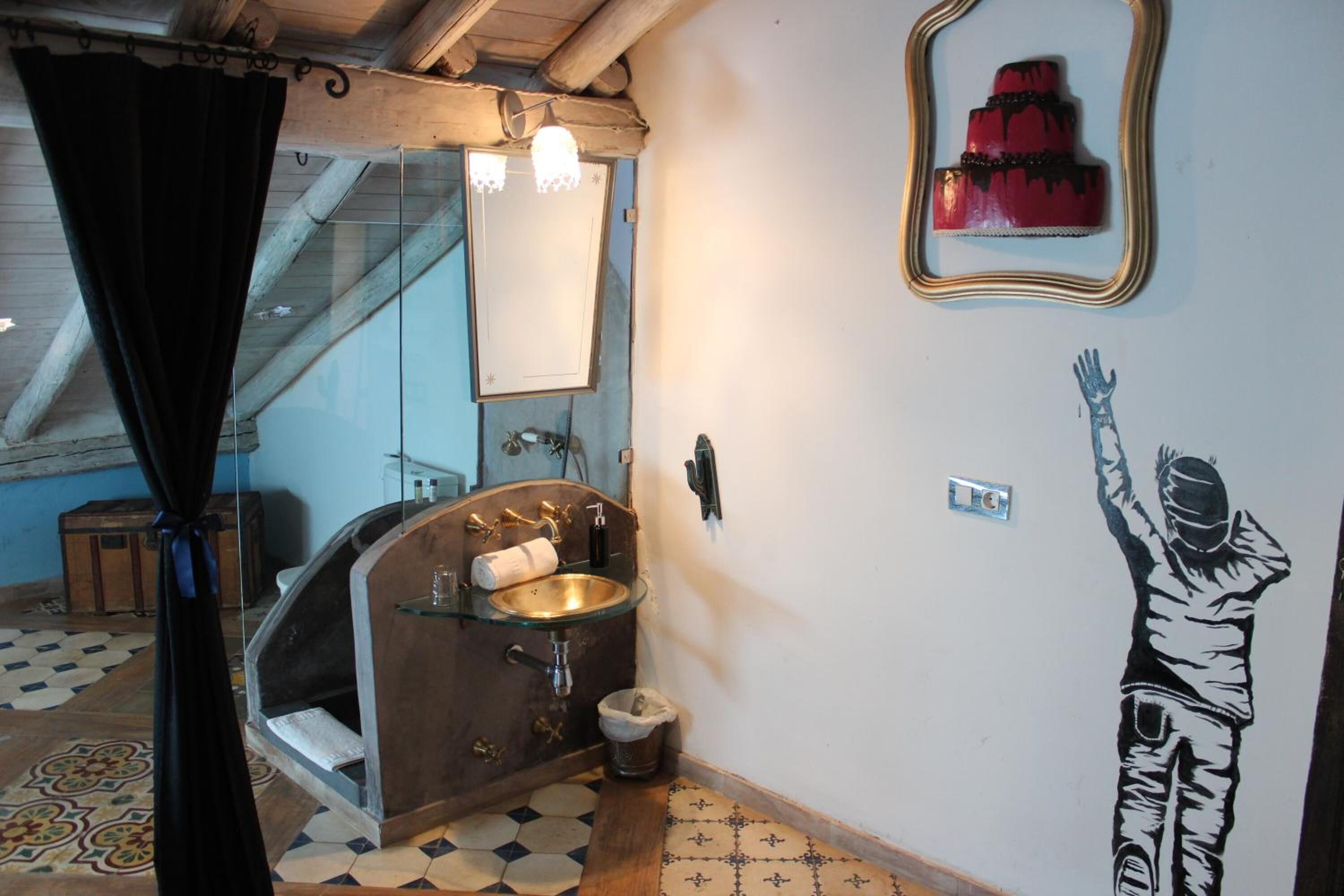 Un baño con lavamanos de vidrio, un espejo y una lámpara fijada en la pared.