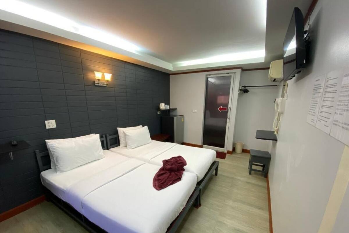 A hotel room with a double bed, bedside tables, a TV, a telephone, and a door leading to a bathroom.
