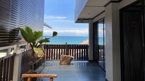 A balcony with a view of the ocean, a wooden table, and a potted plant. - Sinsamut Koh Samed Hotel (Rayong)