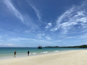 A beach with a clear sky, calm sea, and a distant boat. - Sinsamut Koh Samed Hotel (Rayong)