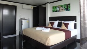 A hotel room with a large bed, a wardrobe, a small refrigerator, and a ceiling light. - Sinsamut Koh Samed Hotel (Rayong)